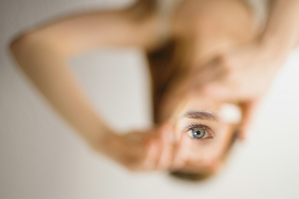 A woman framing one eye with her hands, softly out of focus
