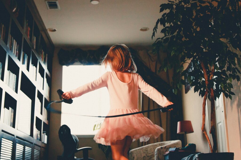 A little girl in a tutu dancing in a sunlit room