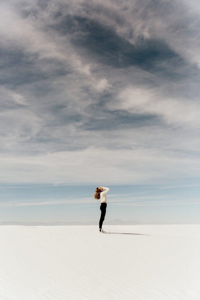 A person stretching on an open beach under a cloudy sky