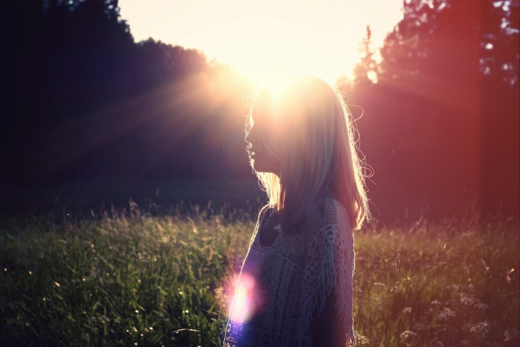 A woman standing in a field in warm evening sunlight